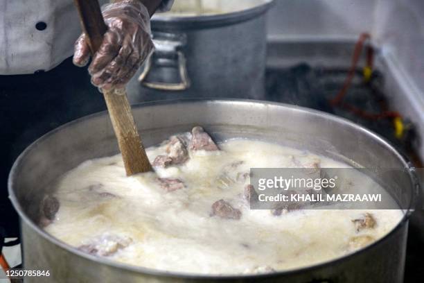 Cook prepares a pot of the traditional Jordanian dish "Mansaf" at a restaurant kitchen in Amman on March 16, 2023. - The kingdom's national dish was...