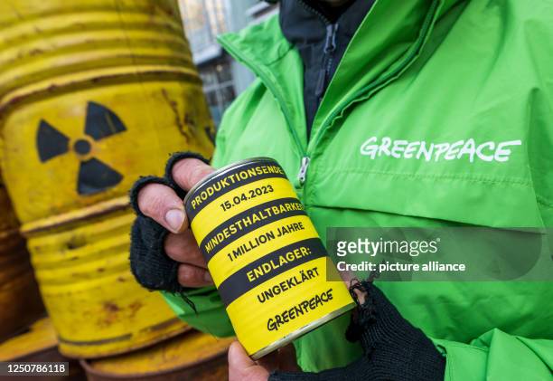 April 2023, Bavaria, Munich: Activists take part with yellow barrels in a Greenpeace demonstration against the lifetime extension of German nuclear...