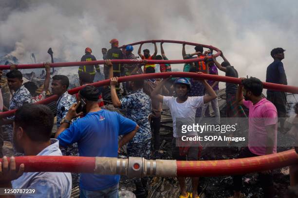 Firefighters and local people try to extinguish a fire that broke out in Bangabazar Market in Dhaka. The fire that took place in Dhaka's Bangabazar...