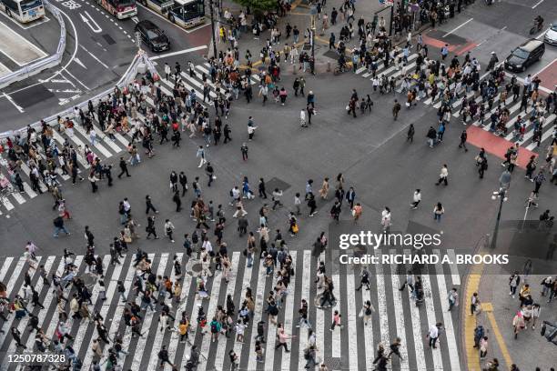 Crowds of people cross the street at Shibuya Crossing, one of the busiest intersections in the world, in the Shibuya district of Tokyo on April 5,...