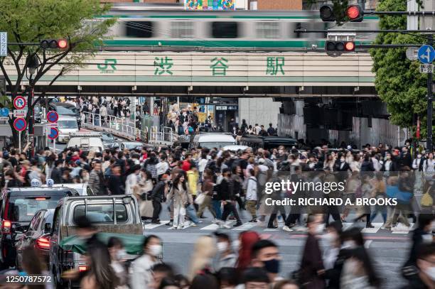 Crowds of people cross the street at Shibuya Crossing, one of the busiest intersections in the world, in the Shibuya district of Tokyo on April 5,...