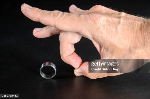 close up of man´s hand flicking wedding ring. - cheating wife stockfoto's en -beelden