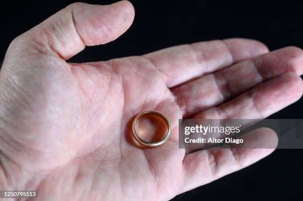 a man has removed his wedding ring and has it on the palm of his hand. - taking off wedding ring stock pictures, royalty-free photos & images