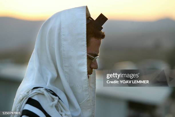 An Israeli settler prays early morning 10 June 2003 next to caravans, as he and other comrades prepare for a possible evacuation of their illegal...