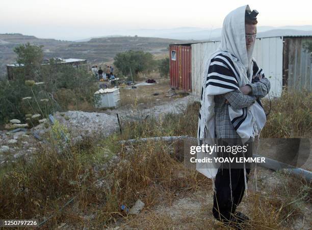 An Israeli settler prays early morning 10 June 2003 next to caravans, as he and other comrades prepare for a possible evacuation of their illegal...