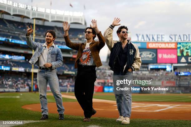 The Jonas Brothers wave to fans before the game between the Philadelphia Phillies and the New York Yankees at Yankee Stadium on April 4, 2023 in New...