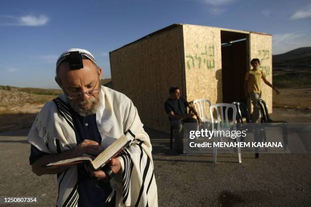 Jewish settler wearing a prayer shawl recites prayers next to a wooden cabin built outside the West Bank settlement Shilo, on June 4 the day after...