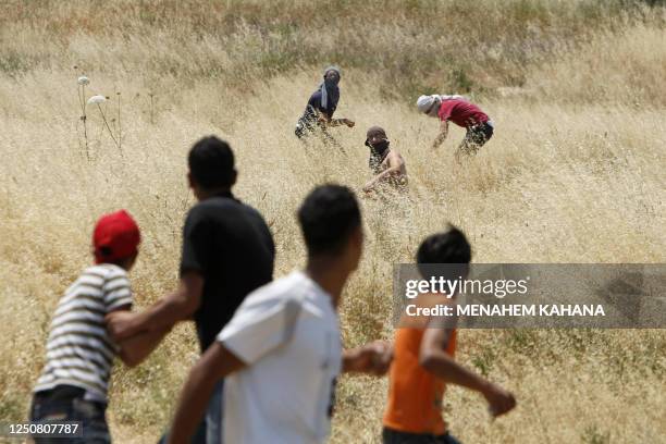 Masked Jewish settlers from the Yitzhar settlement prepare to hurl stones towards Palestinian stonethrowers on the outskirts of Hawara village, just...