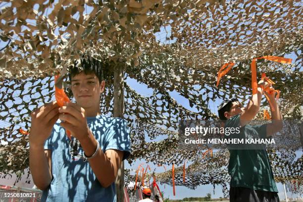 Israeli settlers tie orange ribbons to a new outpost next to Beit Hagay settlement in the West Bank 26 June 2005, as a response to the killing of two...