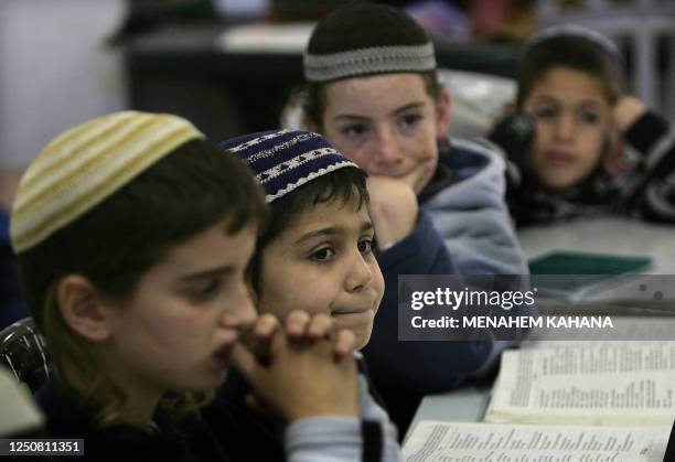 Children of settlers from the Jewish community of the Avraham Avinu settlement in the center of the West Bank city Hebron study the Torah at a house...