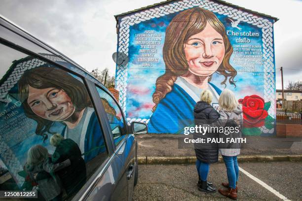 Sisters of Julie Livingstone, Bernadette and Elizabeth, pose in Belfast, on March 28, 2023 by a mural in tribute to their sister, who was killed at...