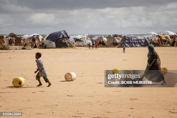 Somali refugee children roll water containers as they bring them back to their makeshift shelter in the Dadaab refugee camp, one of Africa's largest...