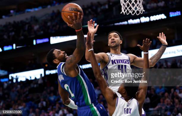 Kyrie Irving of the Dallas Mavericks goes to the basket against Trey Lyles and DeAaron Fox of the Sacramento Kings in the second half at American...