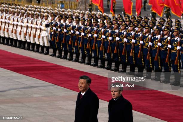 French President Emmanuel Macron walks with Chinese President Xi Jinping after inspecting an honor guard during a welcome ceremony outside the Great...
