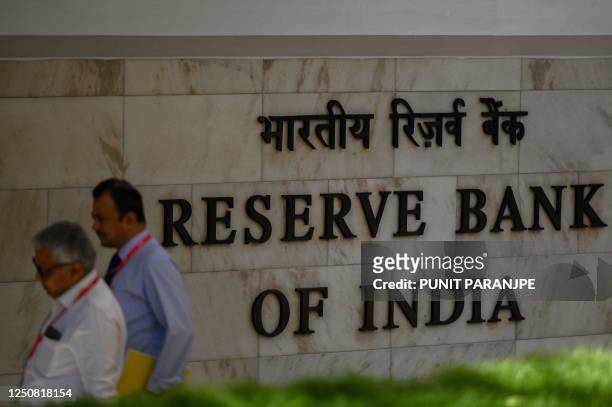 Employees walk past a sign of the Reserve Bank of India in Mumbai on April 6, 2023. - India's central bank held interest rates on April 6 for the...