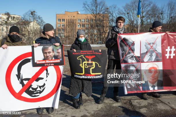 Activists hold portraits of Russian President Vladimir Putin and Russian oligarch Roman Abramovich during a rally demanding German Chancellor Olaf...