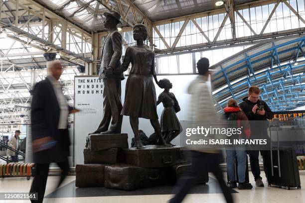 Passengers walk past the National Windrush Monument created by Jamaican artist Basil Watson at Waterloo Station in London on April 6 calling for the...