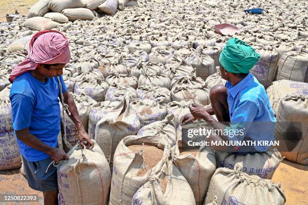 Labourers sew gunny sacks filled with finger millets on the outskirts of Bengaluru on April 6, 2023.