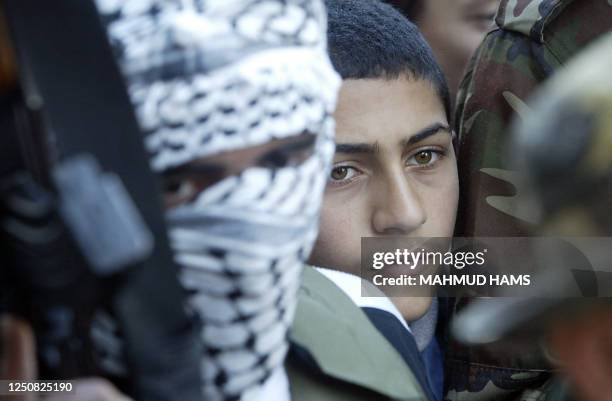 Palestinian boy peers from behind members of the al-Aqsa Martyrs' Brigades, an armed Fatah offshoot, during a press conference in Gaza City 29...