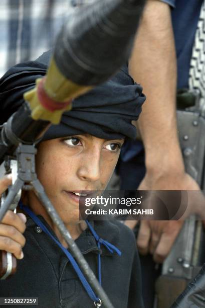 Young boy carries a grenade launcher as militiamen loyal to radical Iraqi Shiite Muslim cleric Moqtada Sadr celebrate after an attack on a police...