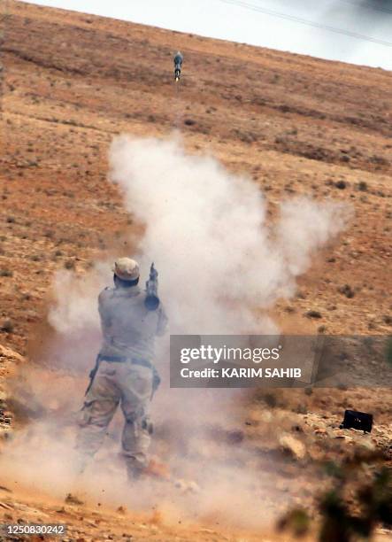 Libyan National Transitional Council fighter fires an RPG from an outpost on the outskirts of the desert city of Bani Walid on October 11, 2011 as...