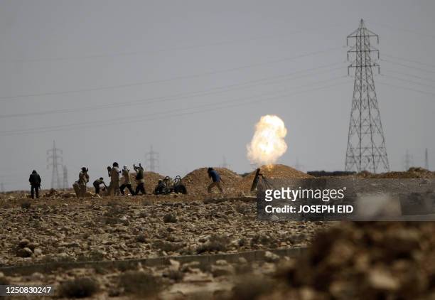 Libyan National Transitional Council fighters fire a 120 mm howitzer on the frontline where fighting with Moamer Kadhafi's loyalists continued on...