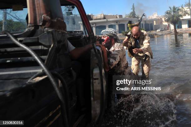 National Transitional Council fighter leans on a pick-up truck after getting shot by a sniper during battles with forces loyal to Moamer Kadhafi in...