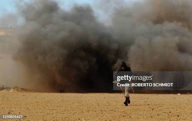 Libyan rebel fighter run for cover as shells explode nearby during a battle with forces loyal to leader Moamer Kadhafi, just few kilometers outside...