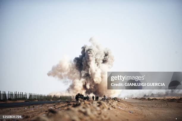 Smoke rises as a Libyan jet fighter drops a bomb on anti Libyan government fighters' position on the outskirt of the eastern oil port town of Ras...