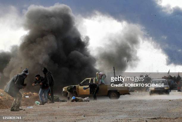 Libyan rebel fighters run for cover as shells explode nearby during clashes with forces loyal to leader Moamer Kadhafi, just few kilometers outside...
