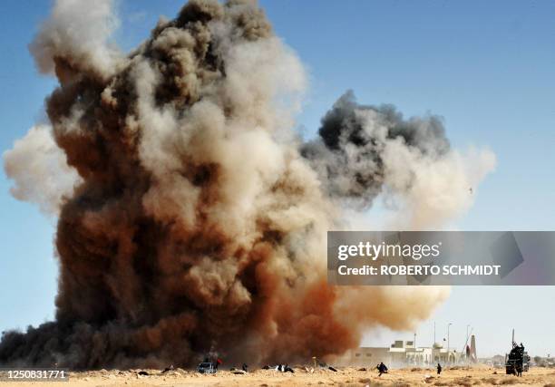 Bomb dropped by a Kadhafi loyalist Airforce fighter jet explodes as Libyan rebel fighters run for cover on March 11, 2011 some 10 kilometers east of...