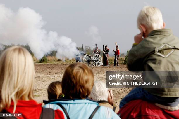 People watch as men wearing traditional attire participate in a re-enactment of a battle at the base of the renovated monument 'The Pyramid of...
