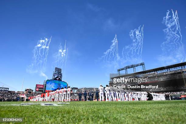 Members of the Washington Nationals and Colorado Rockies are seen on the base path during the singing of the national anthem prior to the game at...