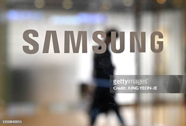 Man walks past the Samsung logo displayed on a glass door at the company's Seocho building in Seoul on April 7, 2023. - Samsung Electronics said on...