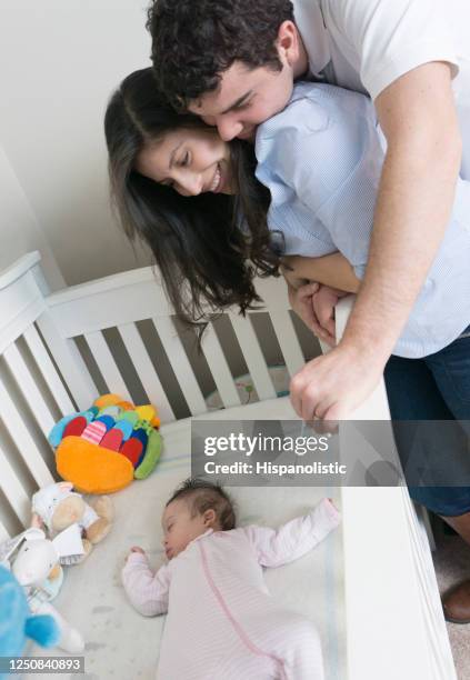 het houden van paar dat hun baby bewondert terwijl zij comfortabel slaapt - baby sleeping stockfoto's en -beelden