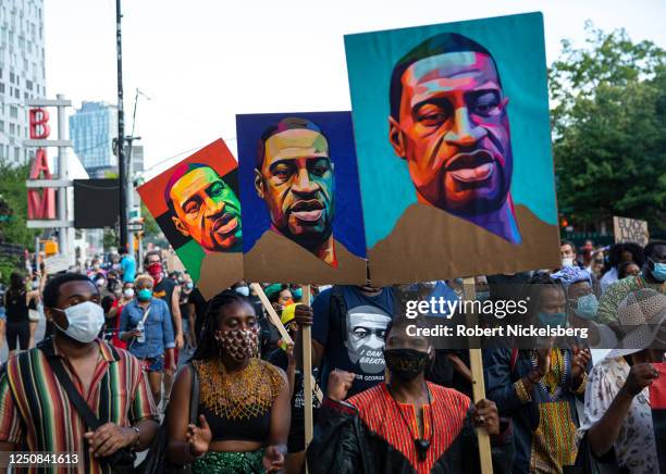 Pedestrians carry posters with the picture of George Floyd who was killed in police custody three weeks earlier in Minneapolis, Minnesota during the...