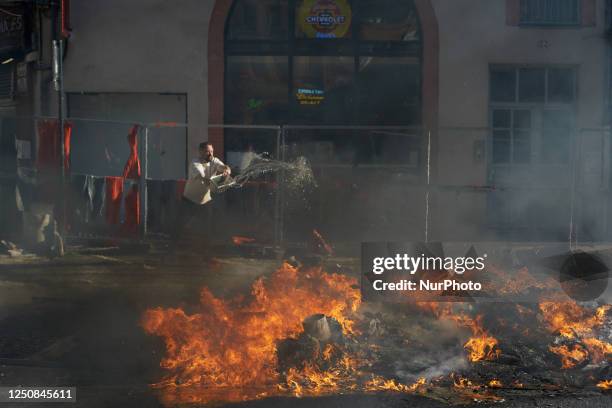 Man tries to extinguish a fire near a restaurant. During the protest riot police used tear gas to cut the cortege in two. They launched scores of...