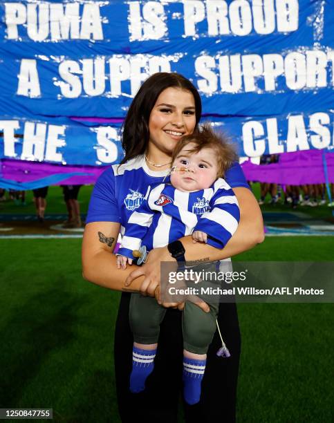 Patients and staff break thru the banner during the 2023 AFL Round 04 match between the North Melbourne Kangaroos and the Carlton Blues at Marvel...