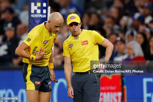 The umpires come together to discuss a goal review during the 2023 AFL Round 04 match between the North Melbourne Kangaroos and the Carlton Blues at...