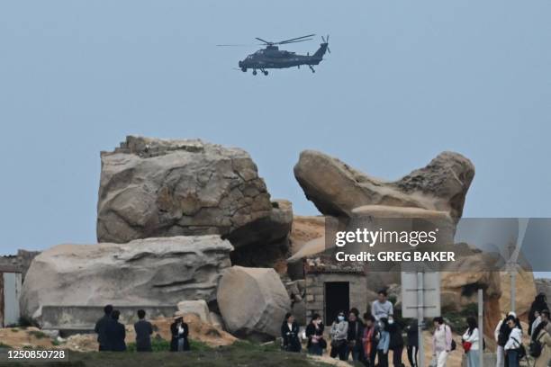 Chinese military helicopter flies past tourists at a viewing point over the Taiwan Strait, on Pingtan island, the closest point to Taiwan, in China's...