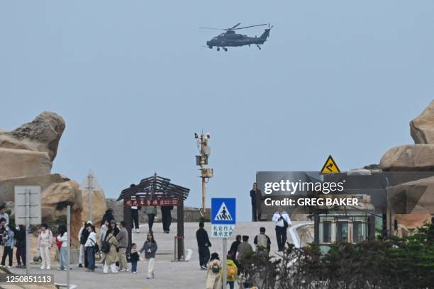 Chinese military helicopter flies past tourists at a viewing point over the Taiwan Strait, on Pingtan island, the closest point to Taiwan, in China's...