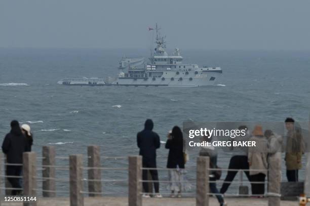 Navy tugboat sails in the Taiwan Strait, past tourists on Pingtan island, the closest point to Taiwan, in China's southeast Fujian province on April...