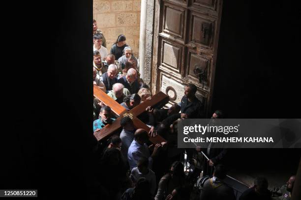 Members of the local Catholic Palestinian parish carry a wooden cross into the church of the Holy Sepulchre in Jerusalem's Old City during the Good...