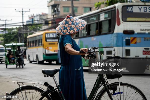 Someone wearing a floral hat walks through a street. On February 1 the military junta government seized power by coup, jailing the...