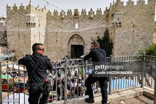 Israeli policemen watch as people gather outside the Damascus Gate leading to the Old City of Jerusalem on April 7 Good Friday to Catholic and...