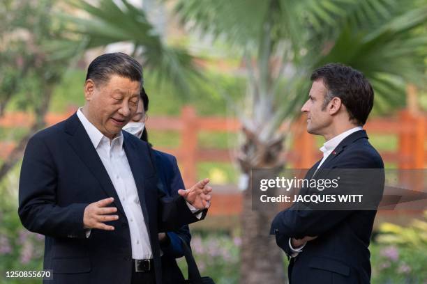 Chinese President Xi Jinping and French President Emmanuel Macron speak as they visit the garden of the residence of the Governor of Guangdong, on...