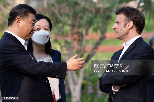Chinese President Xi Jinping and French President Emmanuel Macron speak as they visit the garden of the residence of the Governor of Guangdong, on...