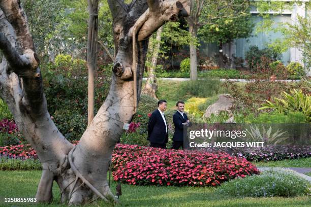 Chinese President Xi Jinping and French President Emmanuel Macron speak as they visit the garden of the residence of the Governor of Guangdong, on...