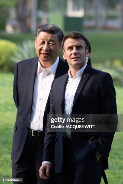 Chinese President Xi Jinping and French President Emmanuel Macron speak as they visit the garden of the residence of the Governor of Guangdong, on...