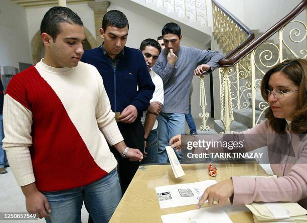 Turkish Cypriot soldier wears symbolic " red and white " Turkish colors sweather and takes his ballot paper that reads " Yes - No " while other...